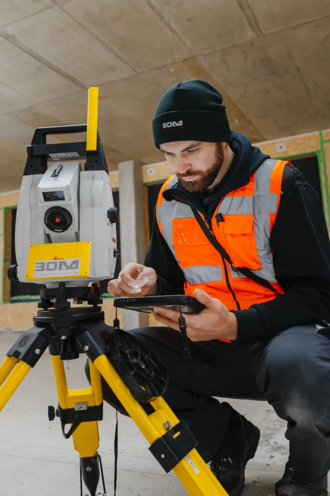 Mitarbeiter richtet die Totalstation auf der Baustelle ein